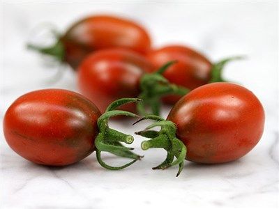 A few small cherry tomatoes, dark red fading to reddish black near green stems