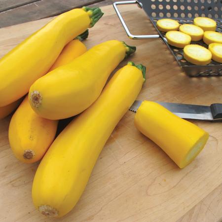 Bright yellow zucchini peppers in a pile on a cutting board, with a few pieces sliced in the background.